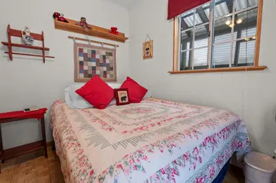 a bedroom with a bed with red pillows on it at Cozy Bear Cottage - Walk to Lake & Village! in Big Bear Lake