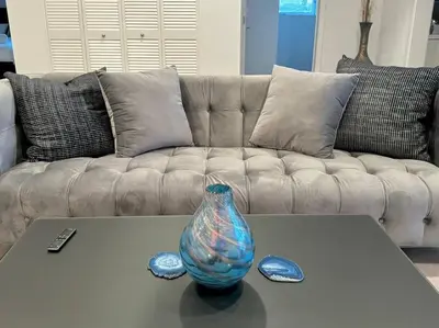 a glass vase on a coffee table in front of a couch at Corner 2 Bedroom 2 Bath Condo - Balcony - Parking in Los Angeles