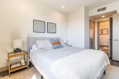 a bedroom with a large white bed and a table at Trendy 2BD 2BTH Apt steps from Downtown Santa Monica! in Los Angeles