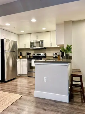 a kitchen with white cabinets and a stainless steel refrigerator at Stunning 2BD 2BTH Apt in Santa Monica! in Los Angeles