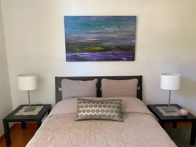 a bedroom with a bed with two lamps and a painting at Lovely one bedroom guest house in Encino village in Los Angeles
