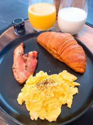 a plate of food with eggs ham and bread and orange juice at Party House Heaven in North Hollywood