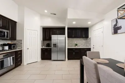 a kitchen with a refrigerator and a table in it at Perfect Home for Work or Relaxing Vacation in Bakersfield