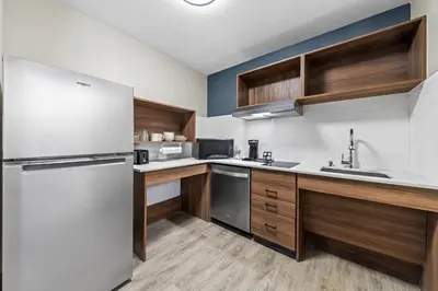a kitchen with a white refrigerator and wooden cabinets at Everhome Suites Ontario in Ontario