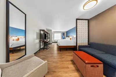 a hotel room with a couch and two beds at Everhome Suites Ontario in Ontario