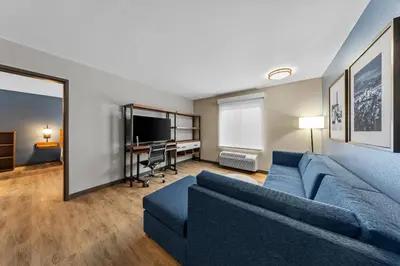 a living room with a blue couch and a desk at Everhome Suites Ontario in Ontario