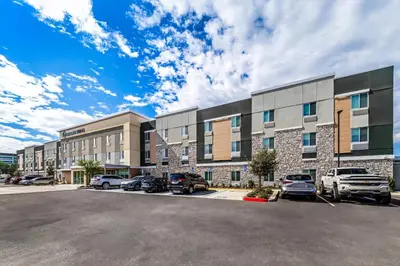 an apartment building with cars parked in a parking lot at Everhome Suites Ontario in Ontario