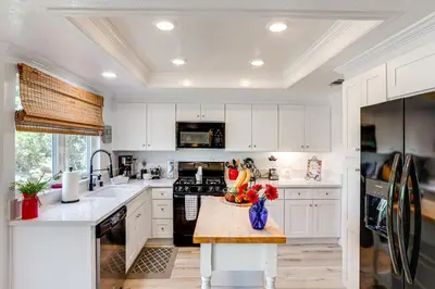 a kitchen with white cabinets and a table with a bowl of fruit at Pet-Friendly Riverside Retreat with Private Spa! in Riverside