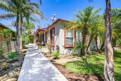 a house with palm trees in front of it at 5 Mi to Coast Centrally Located Long Beach Home! in Long Beach