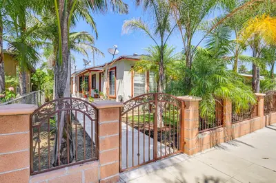 a brick fence with palm trees in front of a house at 5 Mi to Coast Centrally Located Long Beach Home! in Long Beach