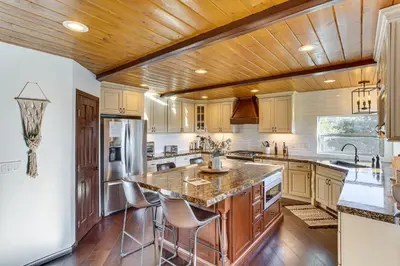 a kitchen with wooden ceilings and a large island with bar stools at Lake Arrowhead Cabin 4 Decks, Game Room and More! in Lake Arrowhead
