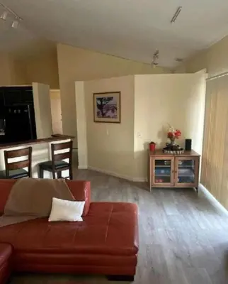 a living room with a red couch and a kitchen at Be our Guest Hm Tampa in Palmdale