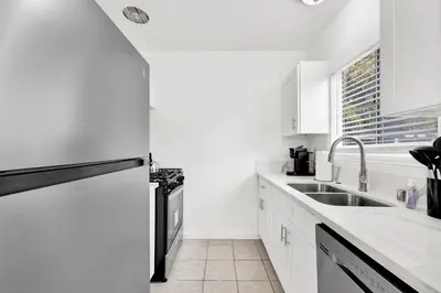 a white kitchen with a sink and a refrigerator at Cozy Elegant Oasis With Parking in Los Angeles