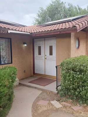 a house with a white door and a gate at Lyons lovely house in Hesperia