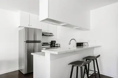 a white kitchen with a sink and two bar stools at Blueground Mid-Wilshire pool nr retail LAX-1266 in Los Angeles