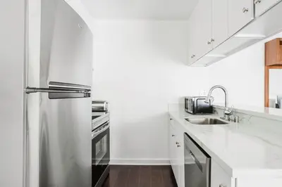 a white kitchen with a refrigerator and a sink at Blueground Mid-Wilshire pool nr retail LAX-1266 in Los Angeles