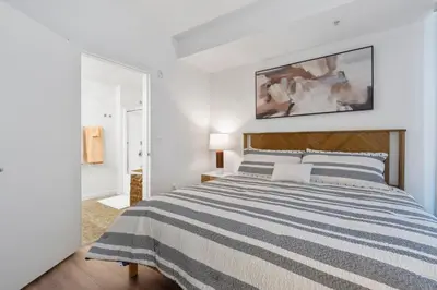a white bedroom with a bed with a striped blanket at 14 Santa Monica Gorgeous Apartment in Los Angeles