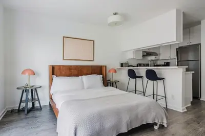 a bedroom with a bed and two chairs and a kitchen at Blueground Mid-Wilshire pool ac nr retail LAX-1265 in Los Angeles