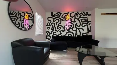 a living room with a black couch and a glass table at 2BR Lit and Spacious in the Heart of Hollywood in Los Angeles
