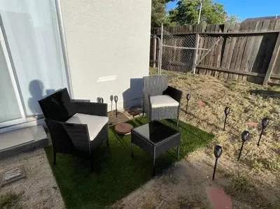a patio with two chairs and a table on grass at Pristine & Smart freshly remodeled house! in Lancaster