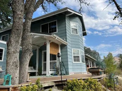 a blue house with a porch and a tree at Mountain View Home in Kernville