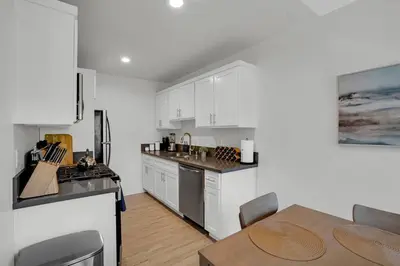 a kitchen with white cabinets and a table in it at 6th Haven, Arcade, King Bed, Games, 1 Mile to Beaches in Long Beach