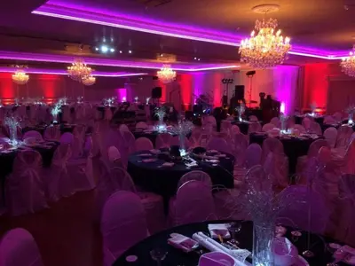 a banquet hall with purple chairs and tables and chandeliers at Hotel Saddleback in Norwalk