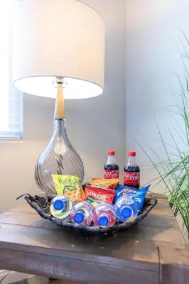 a basket of chips and soda on a table with a lamp at Refreshing and Spotless 4 Bathrooms 22 in Ridgecrest
