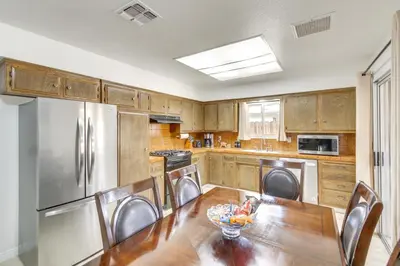 a kitchen with a wooden table and stainless steel appliances at Pet-Friendly Ridgecrest Home Near OHV Trails! in Ridgecrest