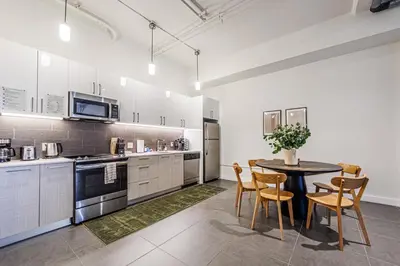 a kitchen with white cabinets and a table and chairs at Downtown Escape - 2BR w Skyline Views & Hot Tub in Los Angeles