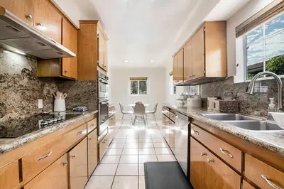 a large kitchen with wooden cabinets and a sink at Updated 3-Bedroom LA Home with Backyard, BBQ & Family-Friendly Amenities in Los Angeles