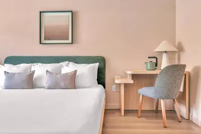 a bedroom with a bed and a chair and a table at City Center Hotel By Kasa in Long Beach