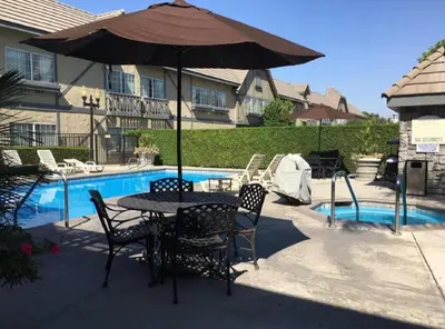 a table and chairs with an umbrella next to a pool at Folk Inn Ontario Airport in Racimo