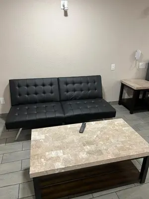 a black couch in a living room with a coffee table at Lone Oak Studio Suites in Bakersfield