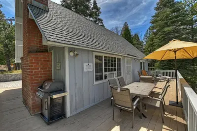 a patio with a table with an umbrella and a grill at Lake Arrowhead Fishermans Haus in Lake Arrowhead