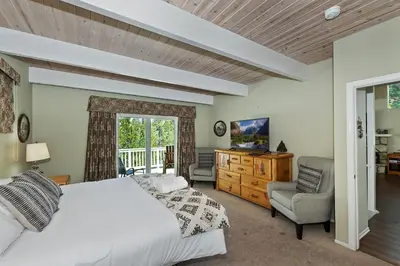 a bedroom with a bed and a chair and a window at Lake Arrowhead Fishermans Haus in Lake Arrowhead