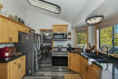 a kitchen with wooden cabinets and a stainless steel refrigerator at Lake Arrowhead Grass Valley Cabin in Lake Arrowhead