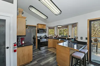 a kitchen with wooden cabinets and black counter tops at Lake Arrowhead Grass Valley Cabin in Lake Arrowhead
