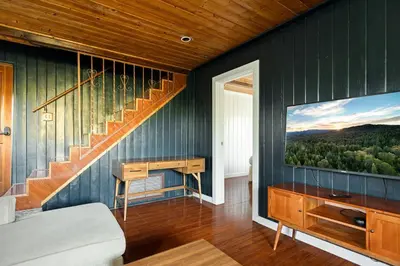a living room with a staircase and a television at Quiet Mountain Cabin in Lake Arrowhead