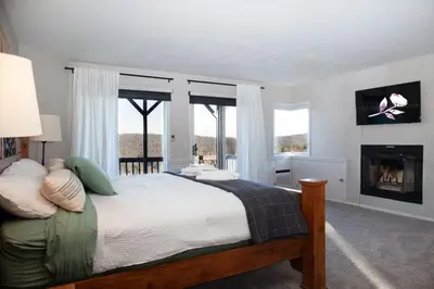 a bedroom with a bed with a fireplace and windows at Lake Arrowhead Matterhorn Views in Lake Arrowhead