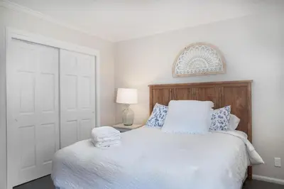 a bedroom with a white bed with a wooden headboard at Lake Arrowhead Matterhorn Views in Lake Arrowhead