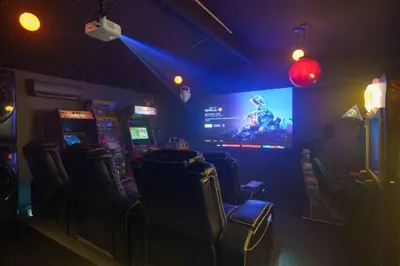 a room with video game machines and a large screen at Pixar Pier by OC Adventure Homes in Anaheim