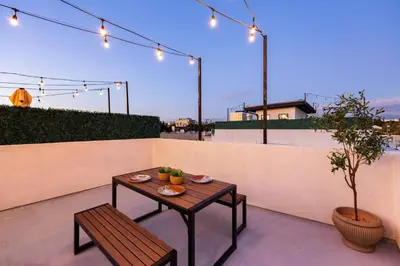 a patio with a table and a bench and lights at Modern Rooftop Villa in Los Angeles