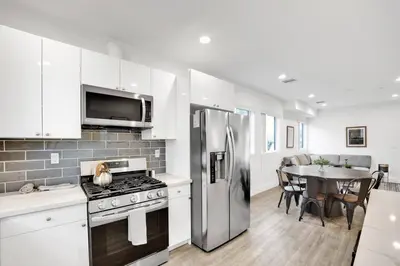 a kitchen with a stainless steel refrigerator and a table at Modern Rooftop Villa in Los Angeles