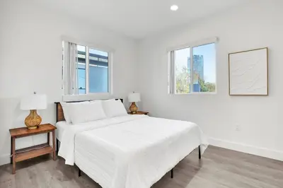 a white bedroom with a bed and two windows at Modern Rooftop Villa in Los Angeles
