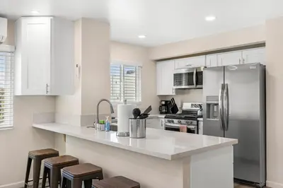 a kitchen with white cabinets and a stainless steel refrigerator at Central Hollywood Apartment in Los Angeles