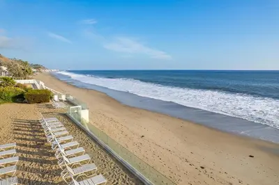 a beach with white lounge chairs and the ocean at Aqualina Best View in Malibu by Stay Awhile Villas in Malibu