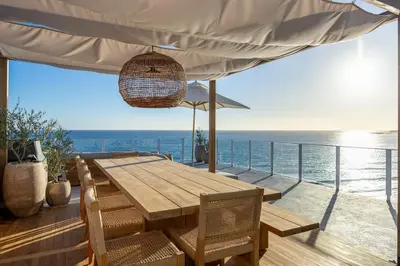 a wooden table and chairs on a deck with the ocean at Aqualina Best View in Malibu by Stay Awhile Villas in Malibu