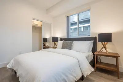 a white bedroom with a bed and a window at LA Cityscapes in Los Angeles