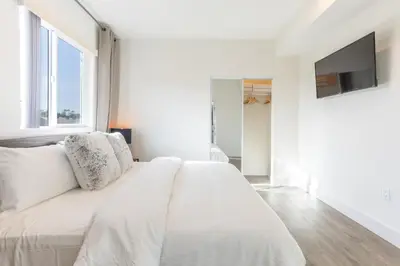 a white bedroom with a large bed and a tv at LA Cityscapes in Los Angeles